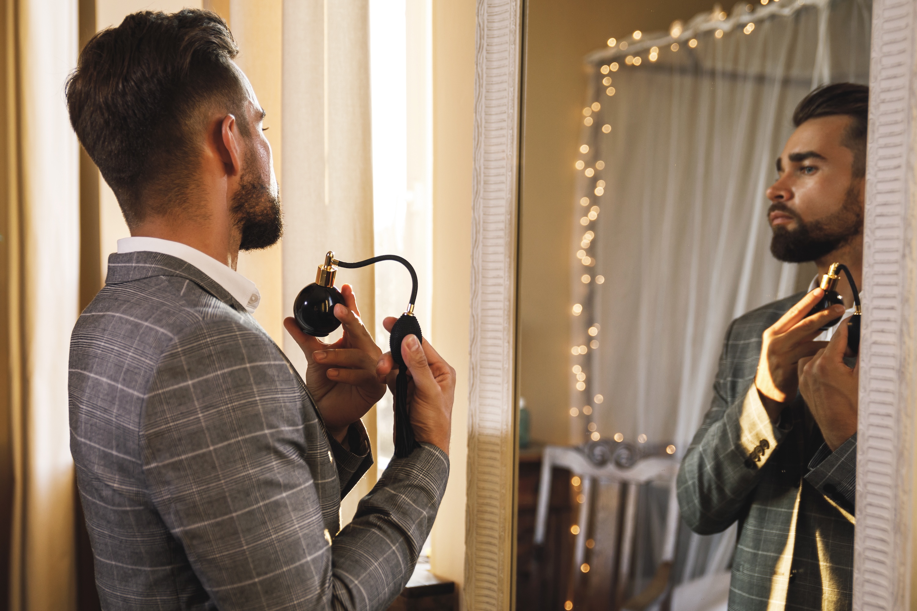 Handsome bearded man is using atomizer nozzle with perfume